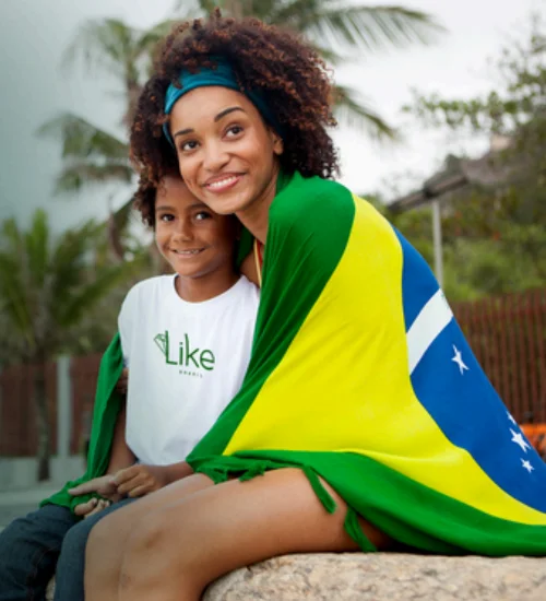 Imagem de uma mãe com a filha com uma bandeira do Brasil e uma camiseta com a logo da Like Brasil